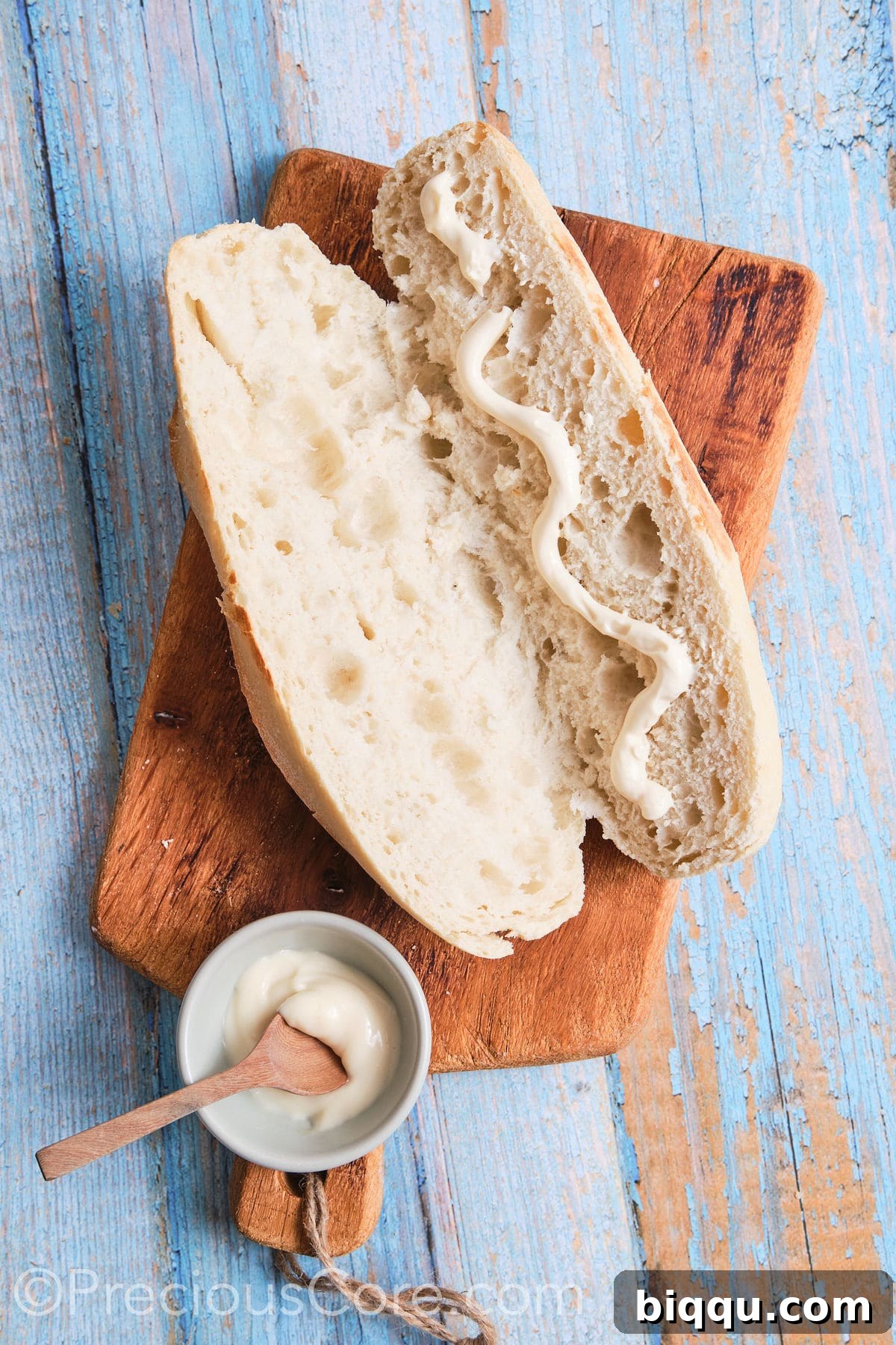 A French baguette with a drizzle of creamy mayonnaise on one side, preparing for the omelette filling.