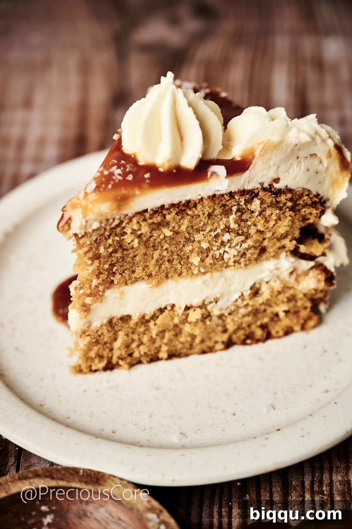 A perfectly sliced piece of salted caramel cake, revealing moist caramel cake layers and fluffy buttercream, ready to be enjoyed.