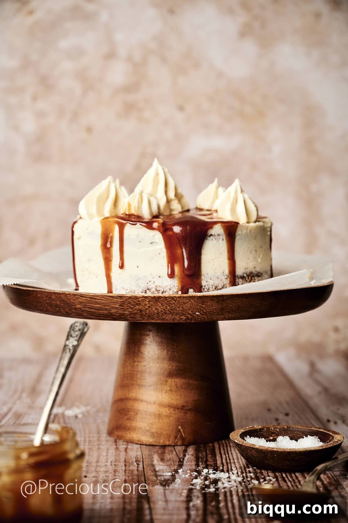 A beautifully frosted Salted Caramel Cake adorned with elegant caramel drips, sitting proudly on a cake stand, ready to be sliced and served.