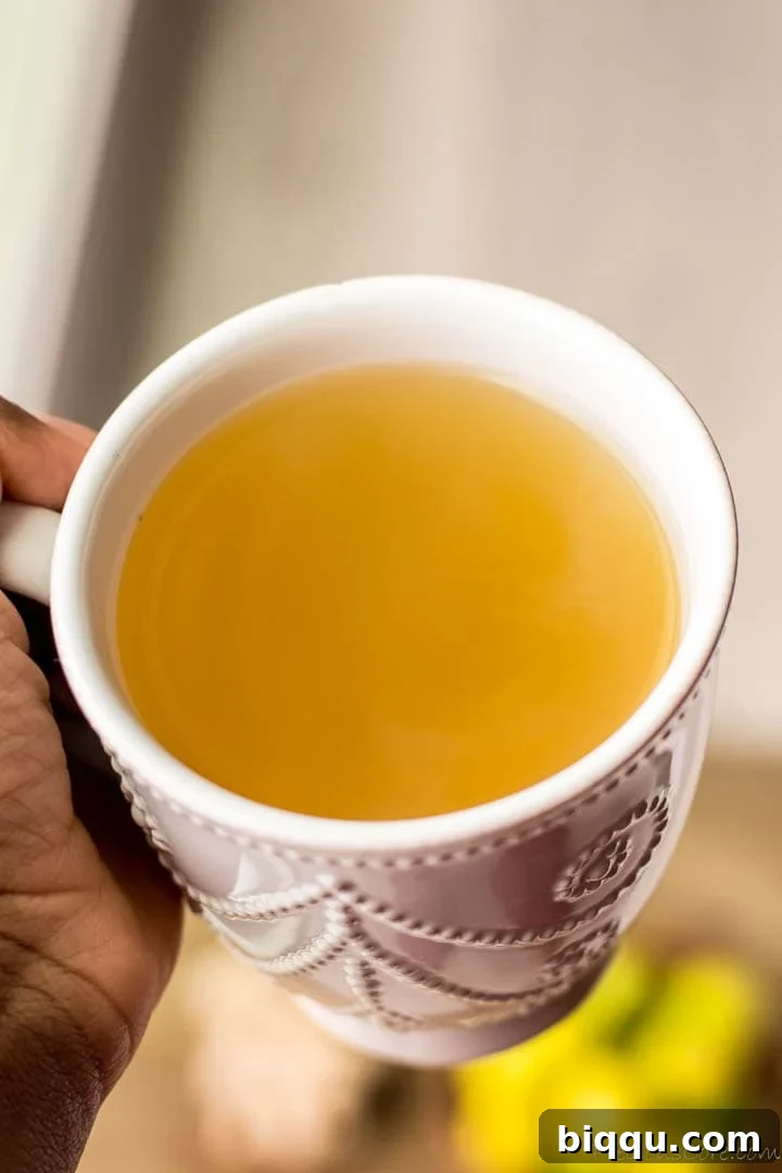 Hand holding a mug of warm ginger tea, symbolizing comfort and health.