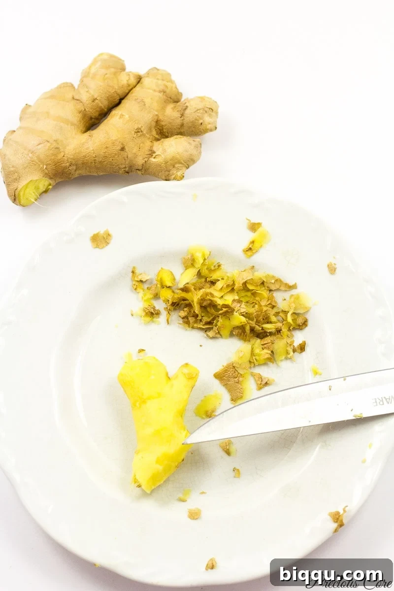 Peeled ginger on a white plate, ready for slicing.