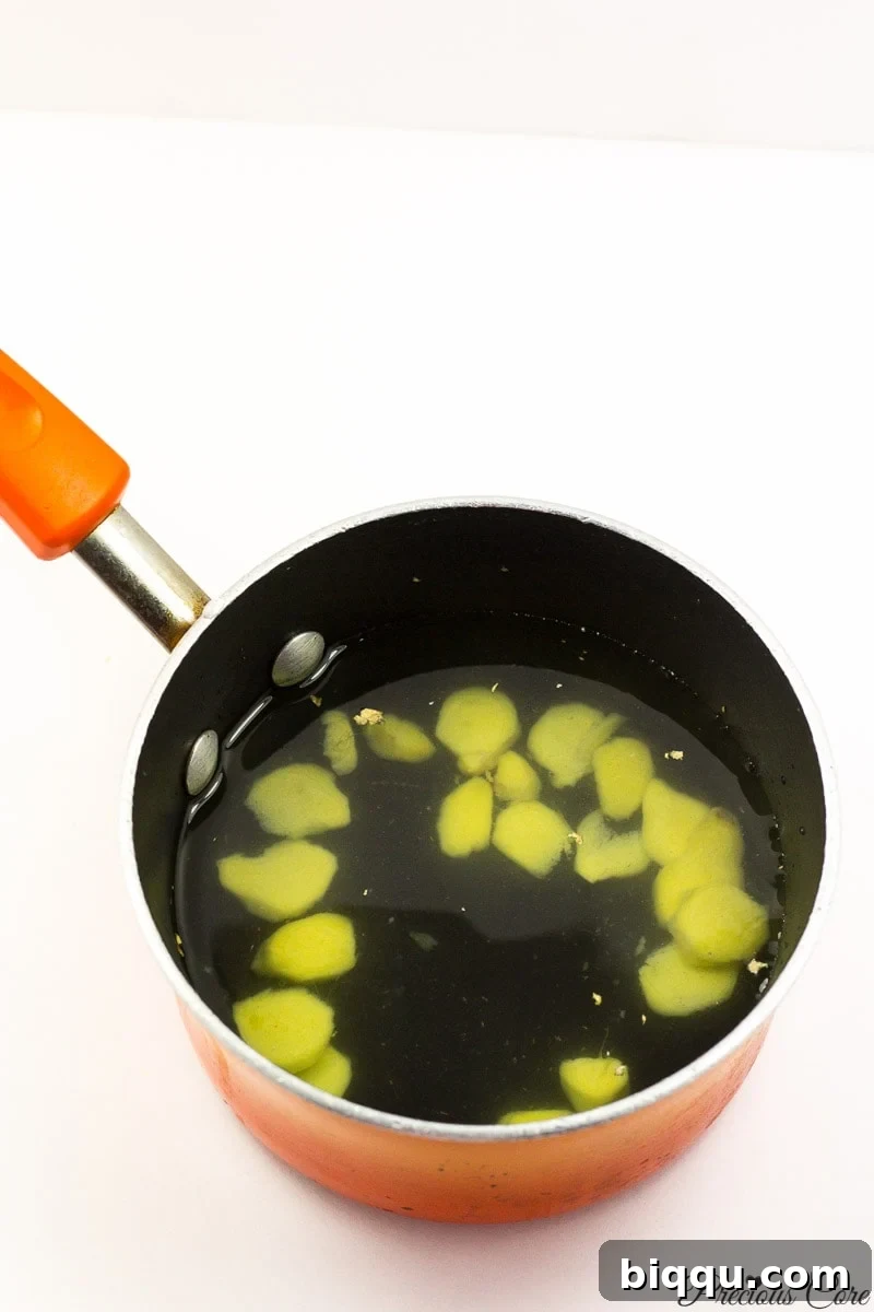 Peeled and sliced ginger placed into a pot with water.
