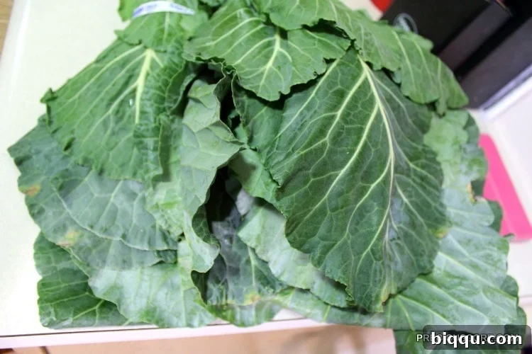 Fresh, vibrant collard greens neatly stacked on a cutting board, prepared for wrapping Ekwang.