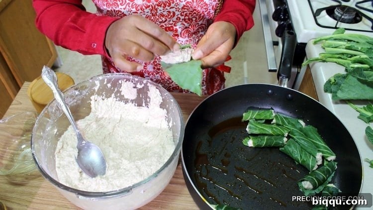 Hands demonstrating the intricate process of wrapping cocoyam paste in green leaves, creating individual Ekwang parcels.