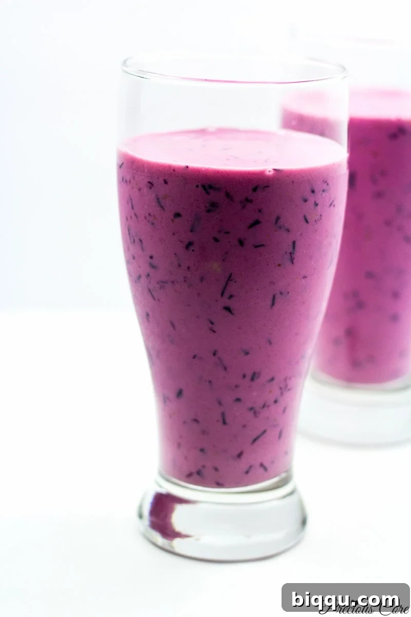 Two tall glasses of a vibrant 4-ingredient purple smoothie, ready to drink.