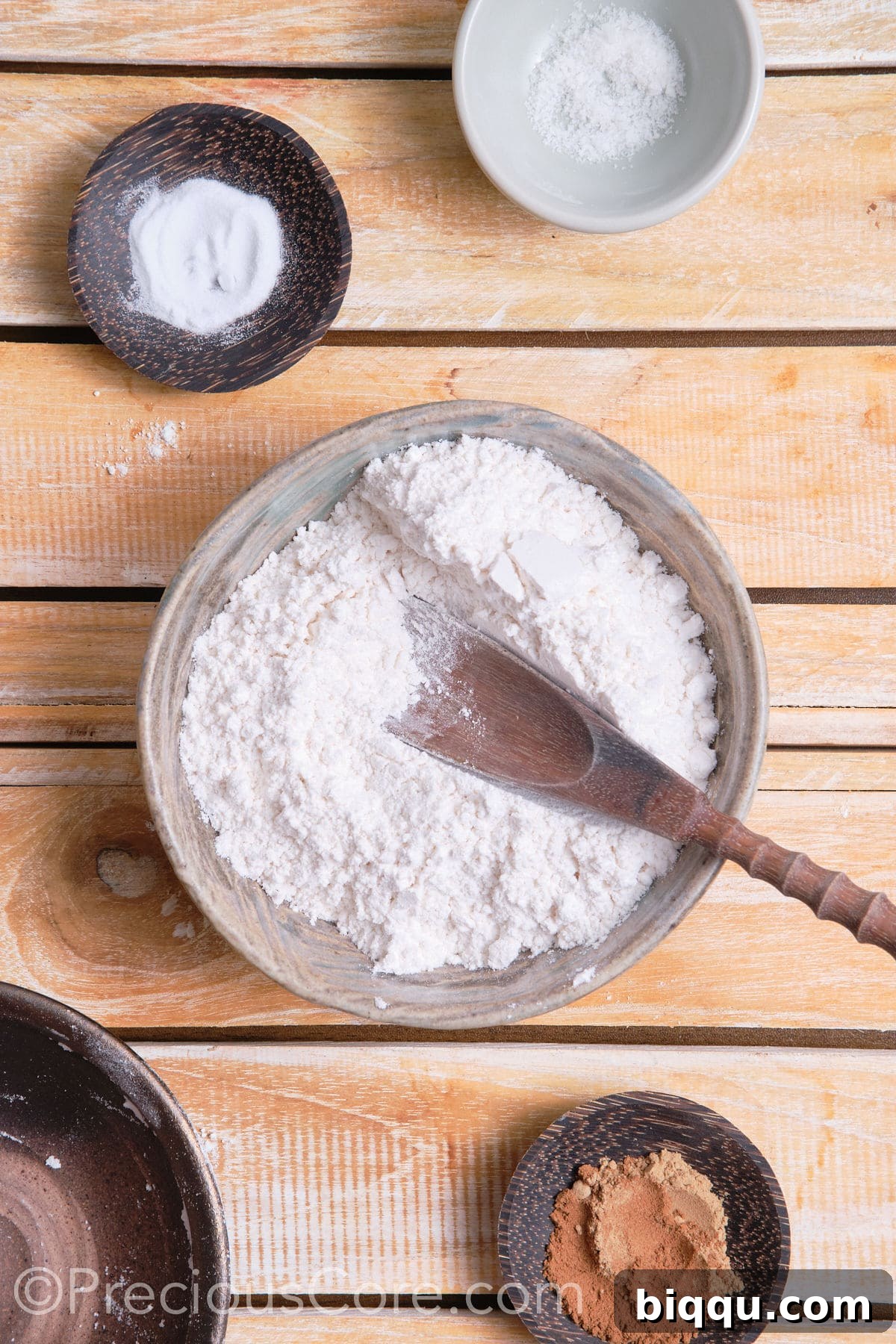 The process of adding dry ingredients like flour, cinnamon, and ginger powder into a mixing bowl, emphasizing careful measurement for cookie preparation.