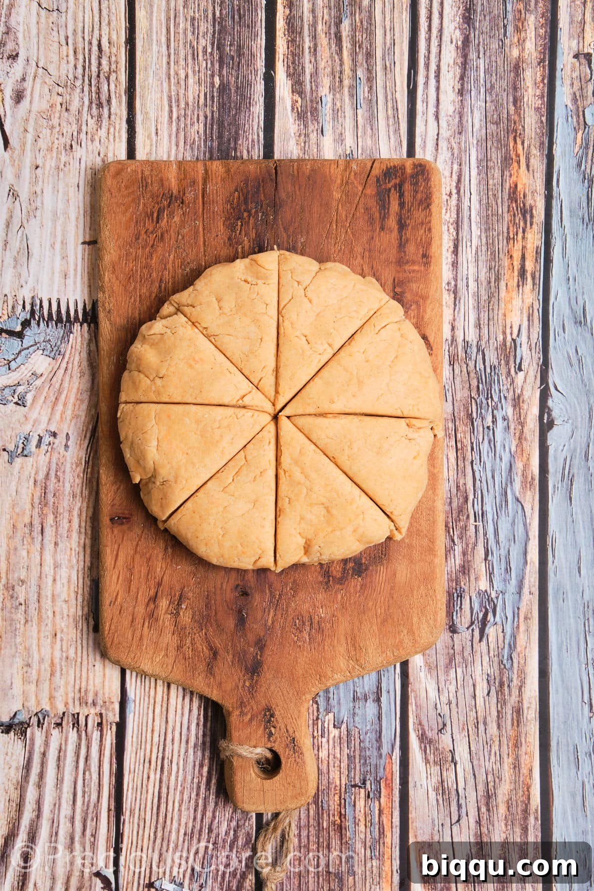 Round shaped dough cut into 8 wedges on a floured surface.