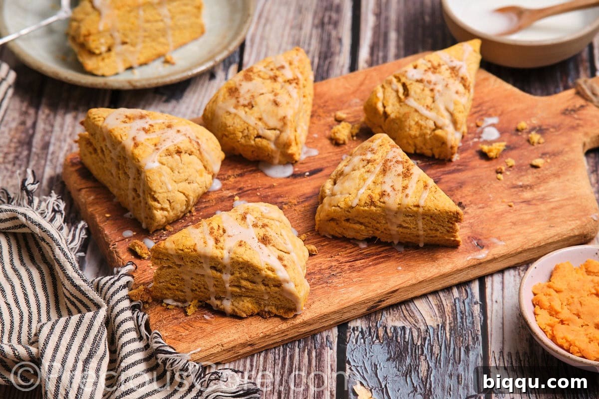 The most delicious scones on a wooden chopping board, garnished with a light glaze.