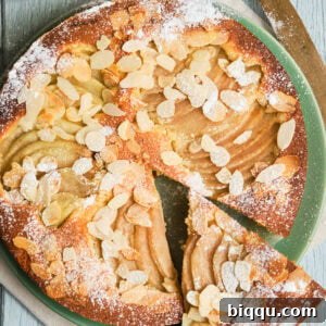 Italian pear almond cake on a plate with a slice cut out.