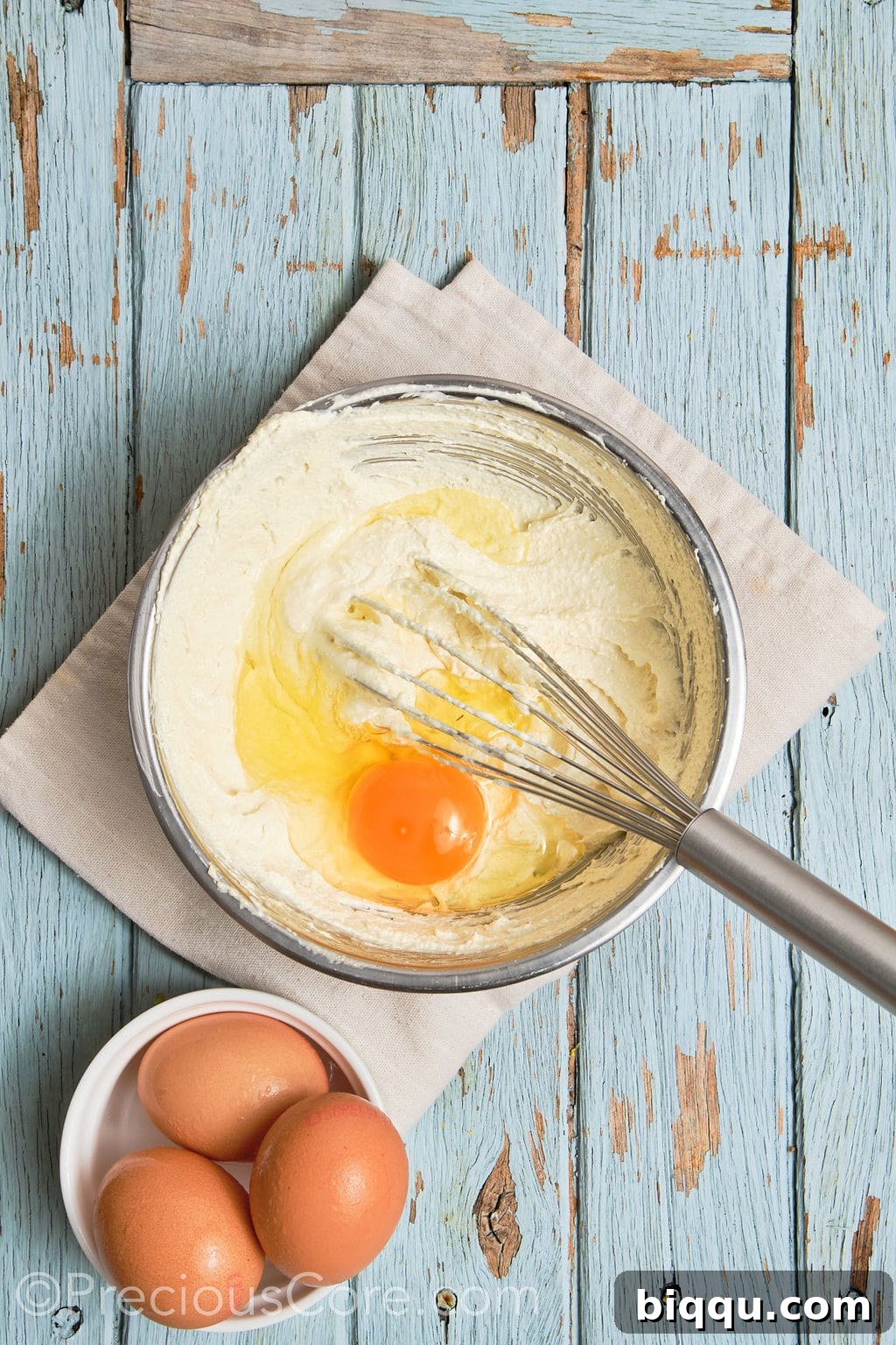 eggs whisked into a creamed butter mixture in a bowl.