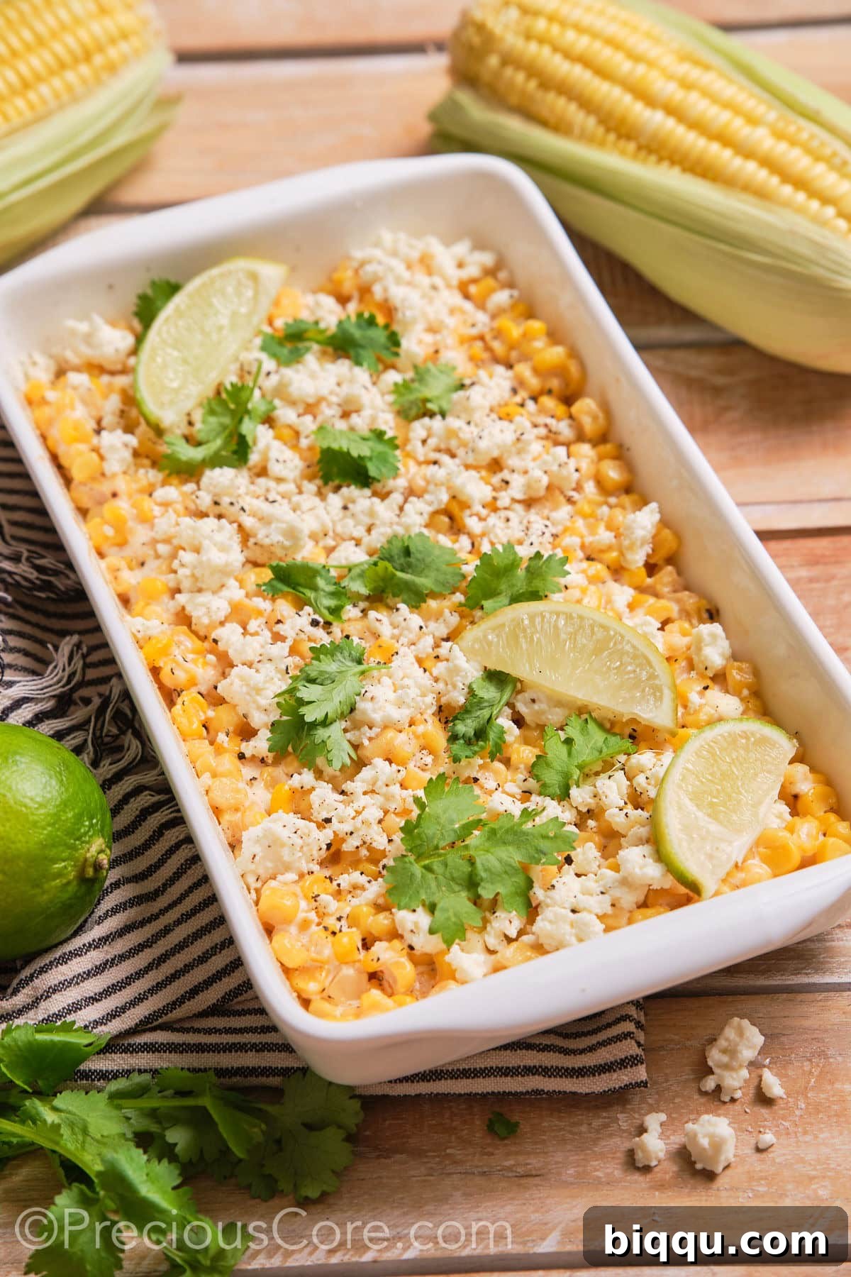 Creamy Mexican Street Corn Casserole in a white baking dish, garnished with fresh cilantro and lime wedges.
