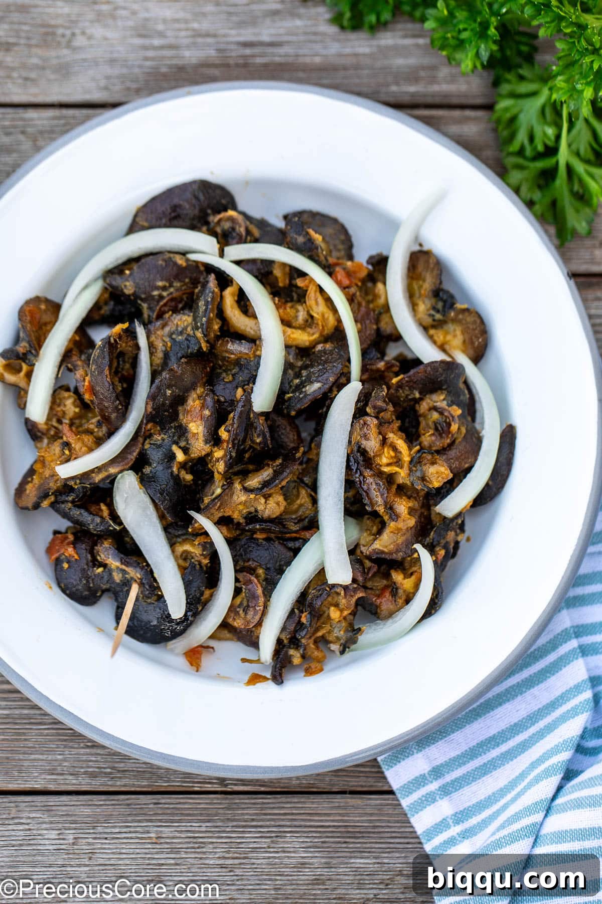 Delicious Cameroonian snails served on a white plate, garnished with fresh sliced onions, ready to be enjoyed.