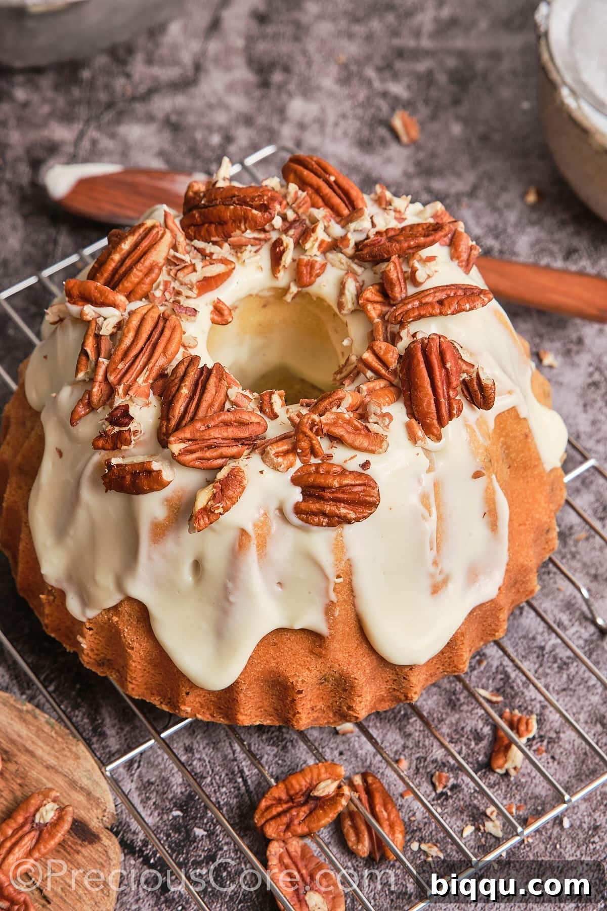 Close-up of a whole Butter Pecan Pound Cake generously covered with creamy frosting and topped with whole pecans.
