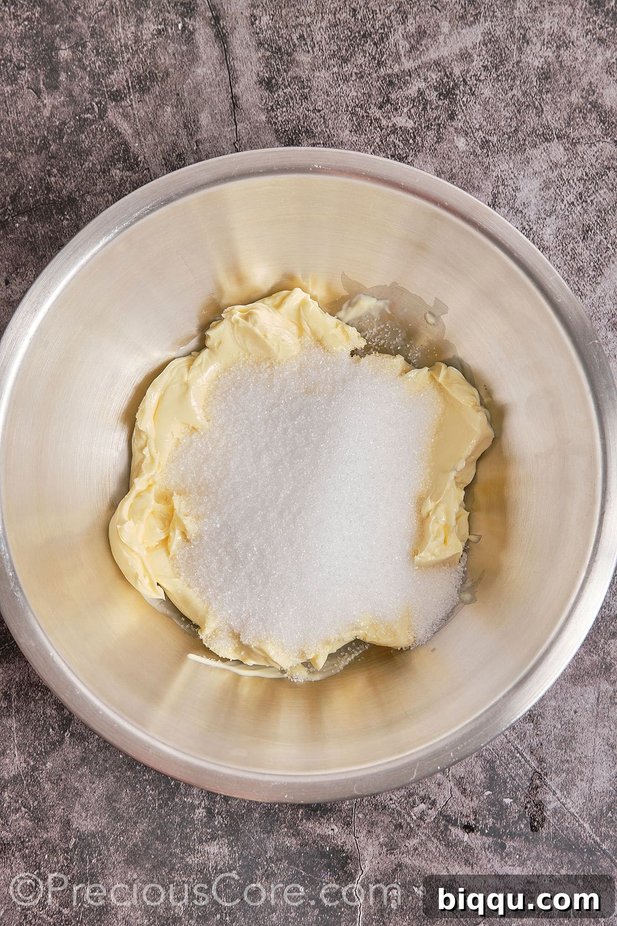 Softened butter and granulated sugar being creamed together in a large mixing bowl with an electric mixer.