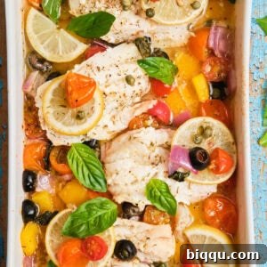 White fish fillets in a casserole dish baked with veggies, beautifully presented for serving.