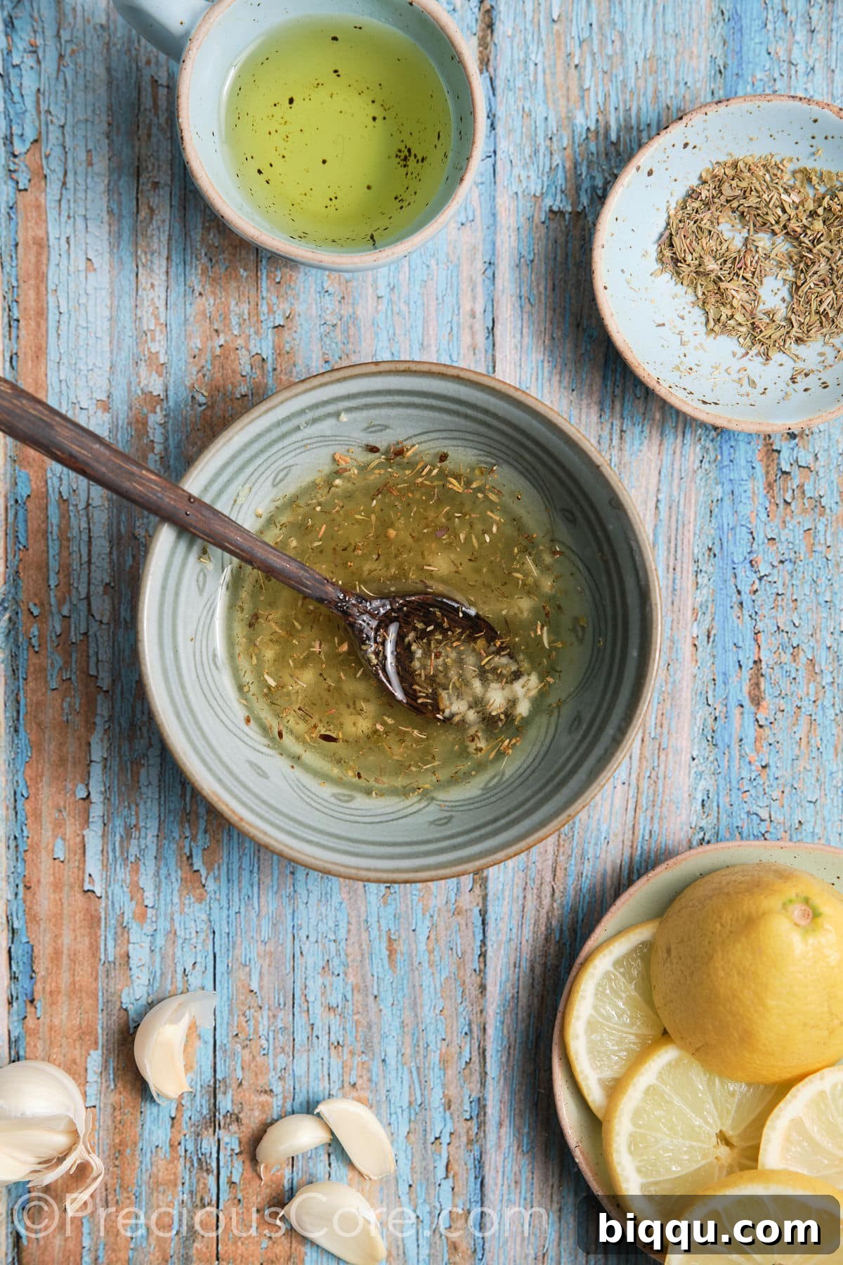 Small bowl containing a freshly prepared marinade with olive oil, minced garlic, dried oregano, dried thyme, and lemon juice.