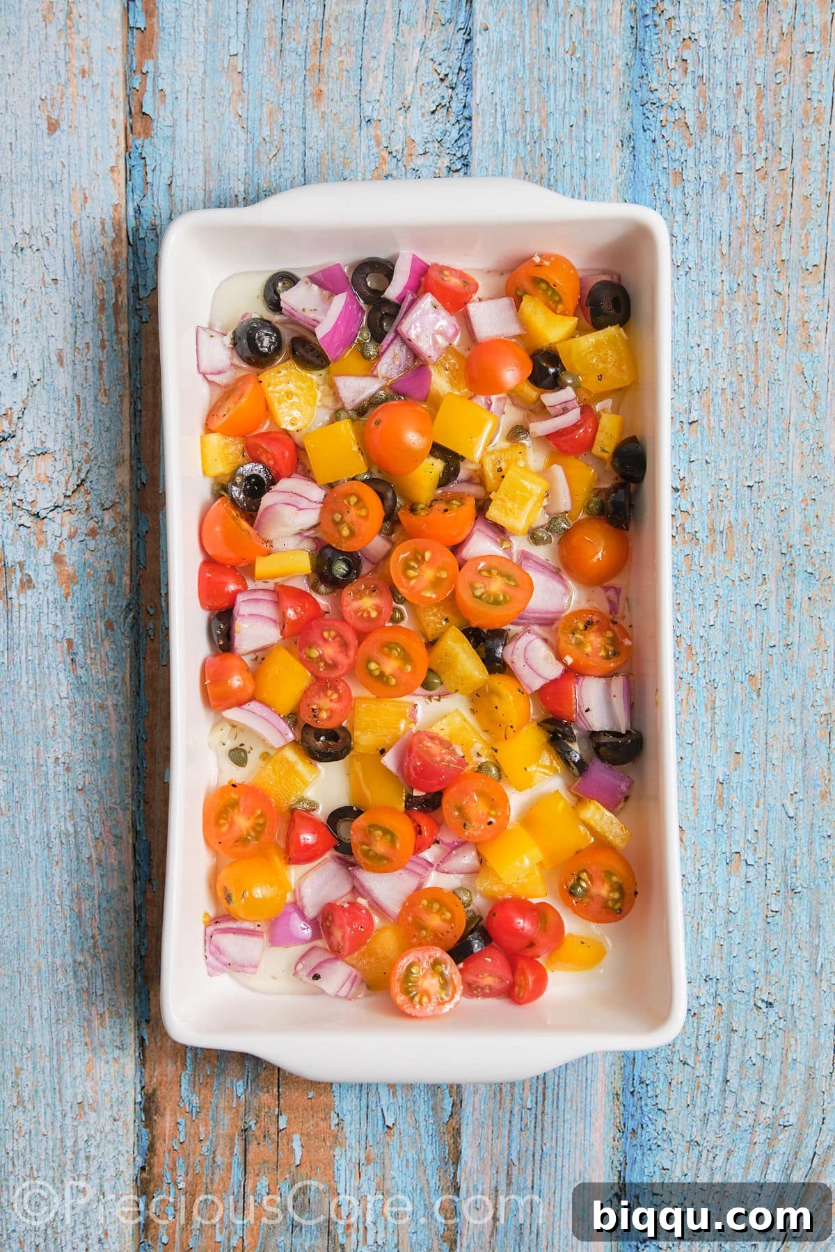 Chopped Mediterranean vegetables evenly arranged in a baking dish, forming a colorful base.