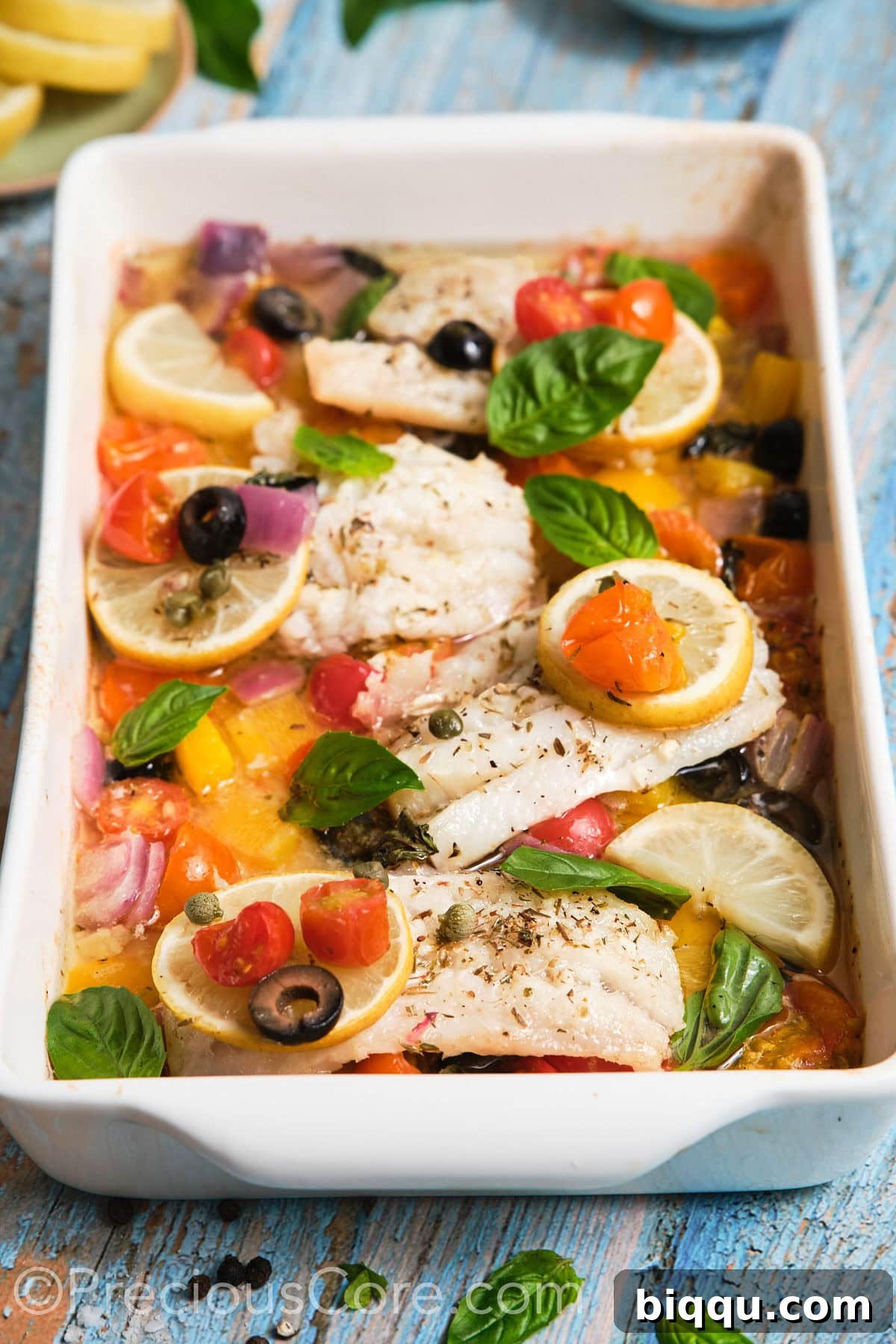 Close-up shot of a single serving of Mediterranean baked fish, showcasing the flaky texture and colorful vegetables.