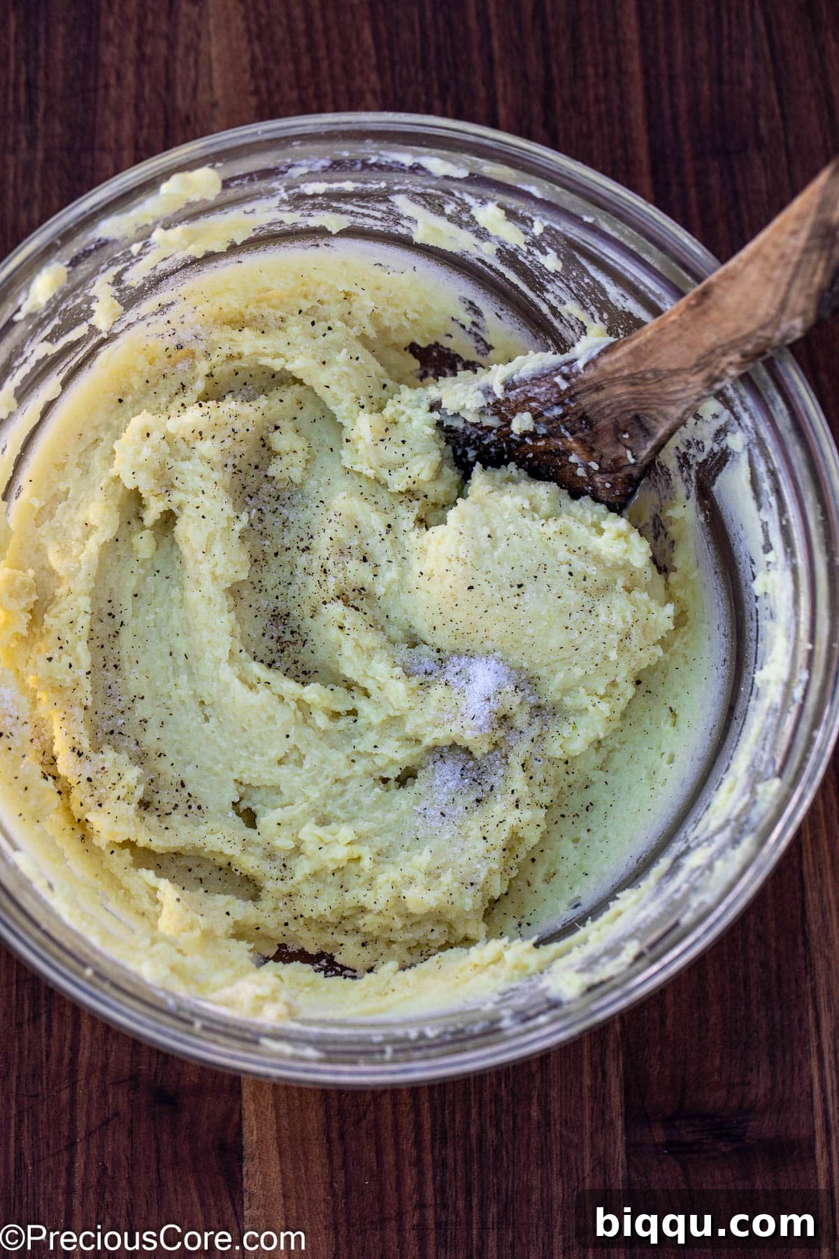 Salt and pepper being sprinkled into the creamy mashed potatoes, ready for final mixing.
