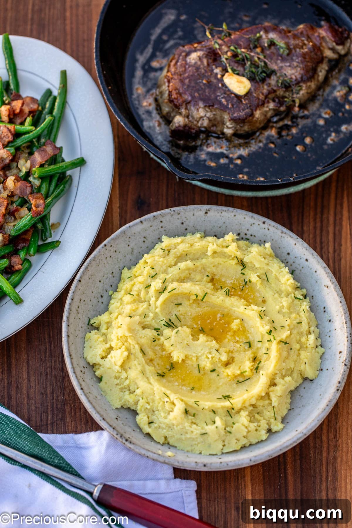 A close-up of creamy mashed white sweet potatoes in a bowl, with melted butter creating delicious pools on top.