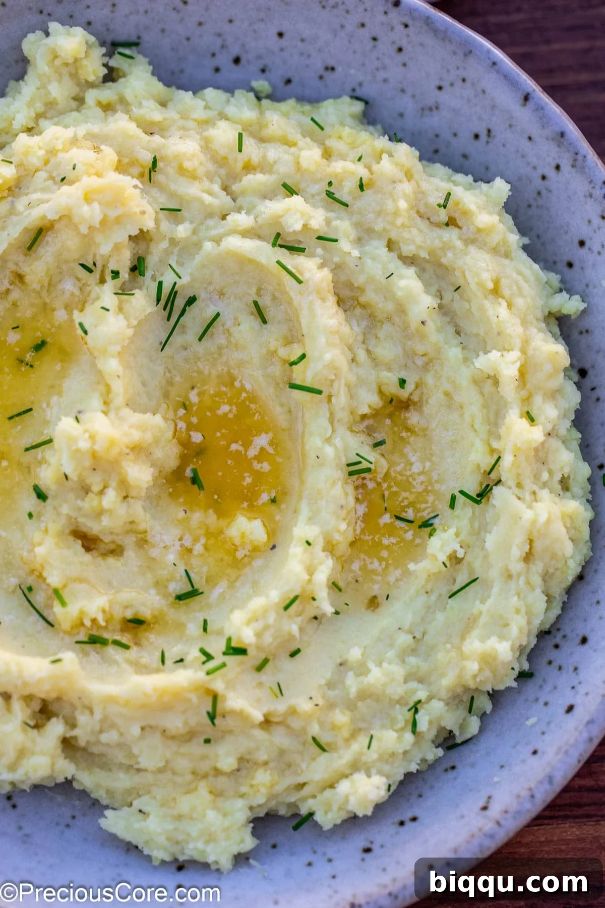 A bowl of creamy mashed white sweet potatoes on a wooden surface, ready to be enjoyed.