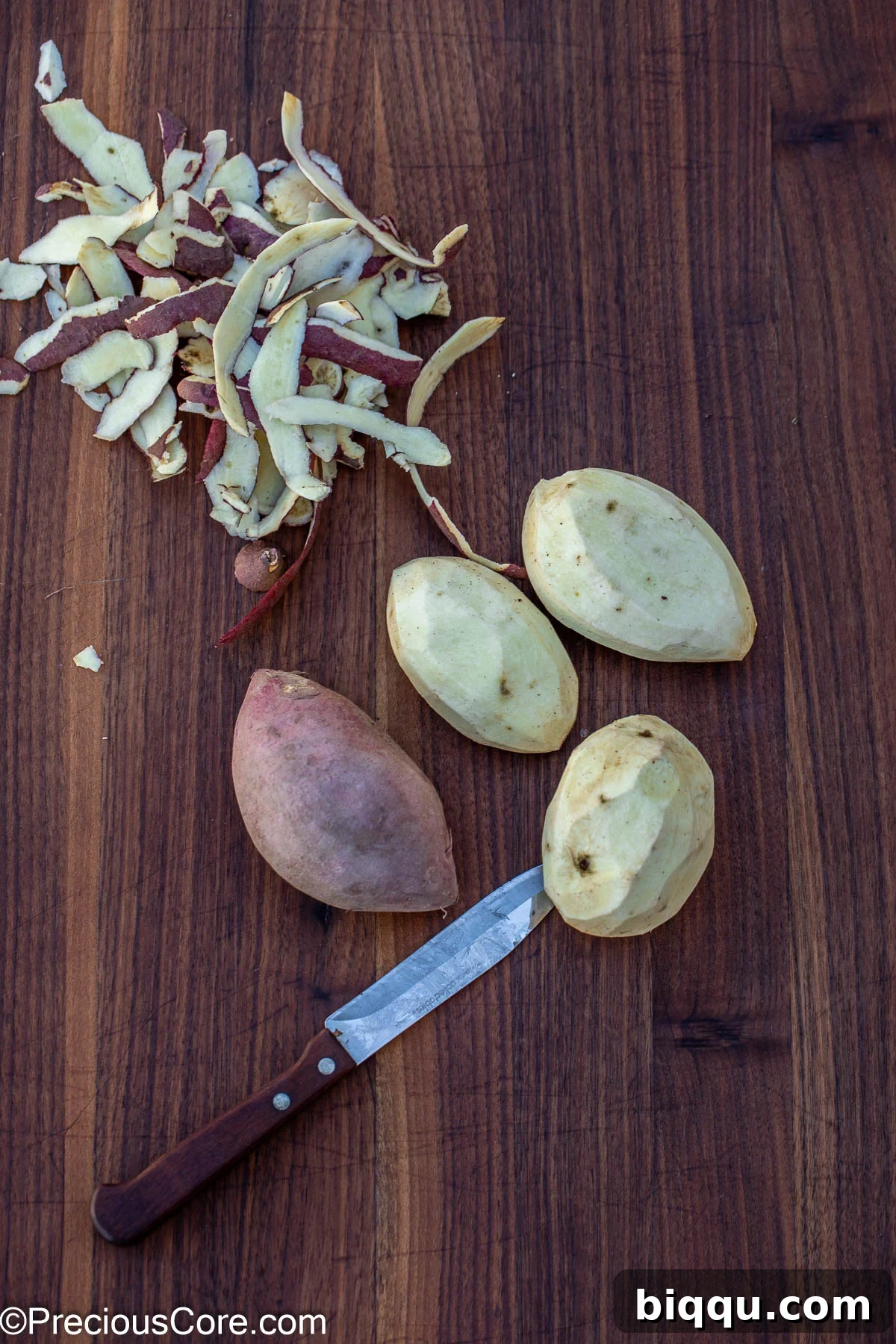 A hand peeling a white sweet potato on a cutting board, preparing it for cooking.