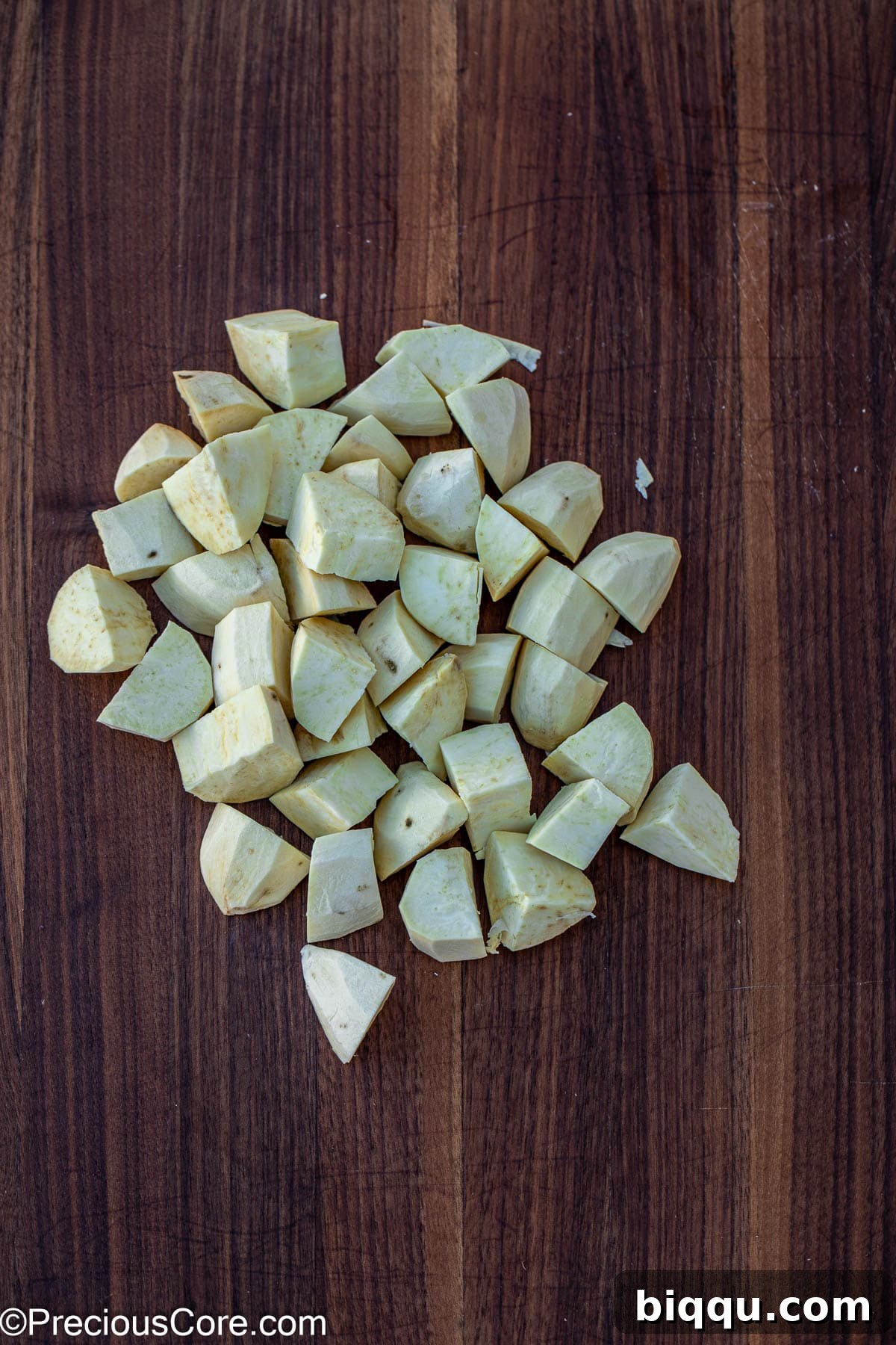 Uniformly diced white sweet potato chunks on a cutting board, ready for boiling.
