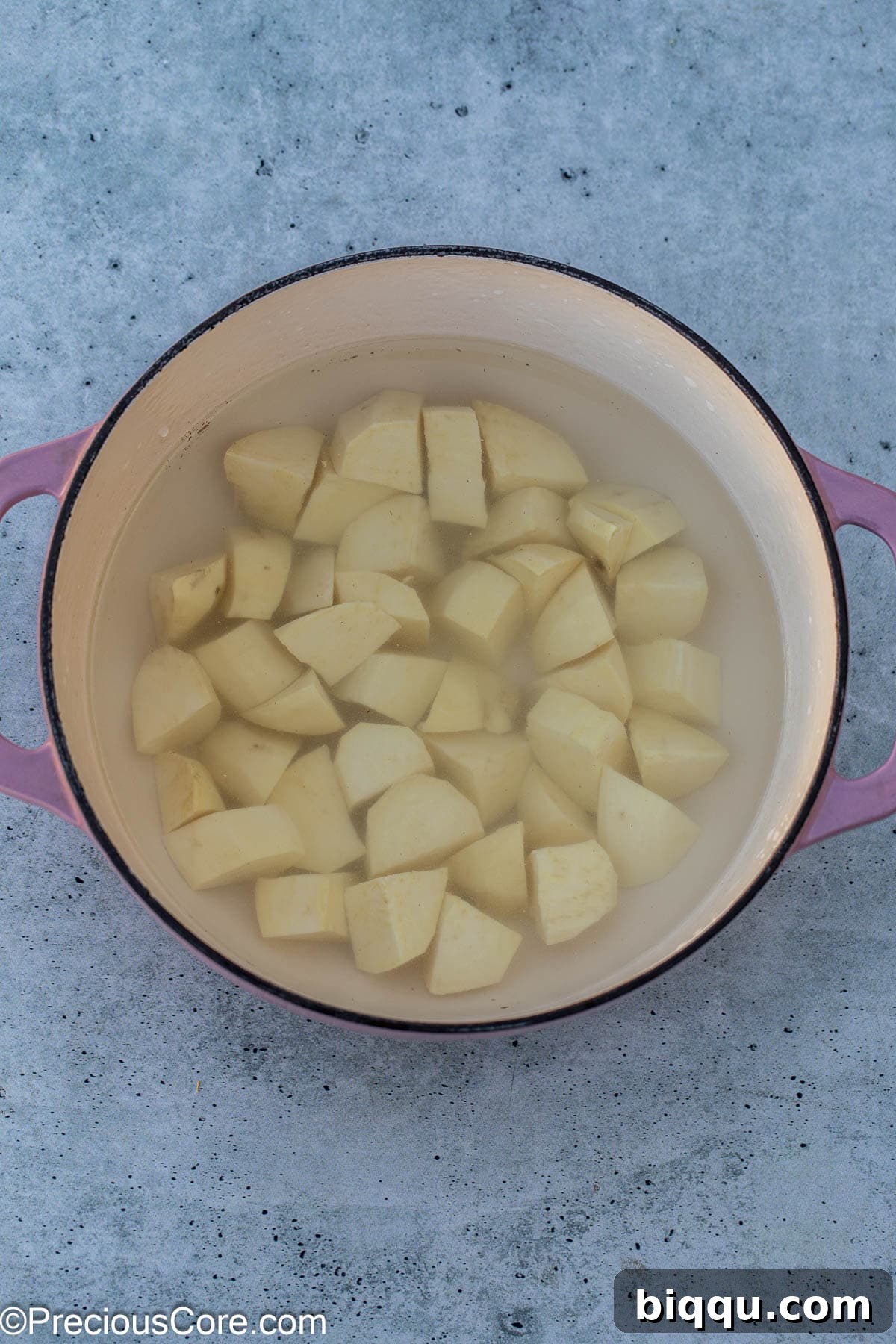 White sweet potato chunks boiling gently in a pot of water on the stovetop.