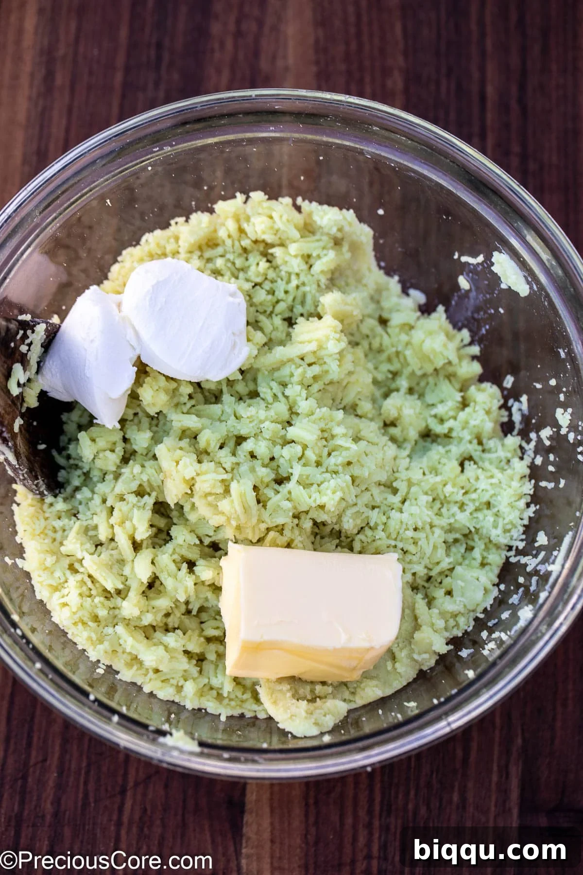 Cream cheese, butter, and milk being added to the mashed white sweet potatoes in a bowl.