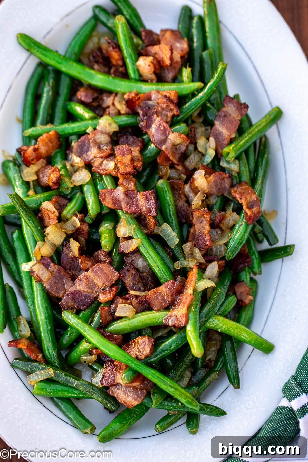 Bacon and green beans on a white tray.