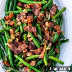 Bacon and green beans on a white tray.