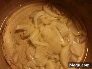 Finely chopped onions sautéing in a pot with oil until translucent and fragrant.