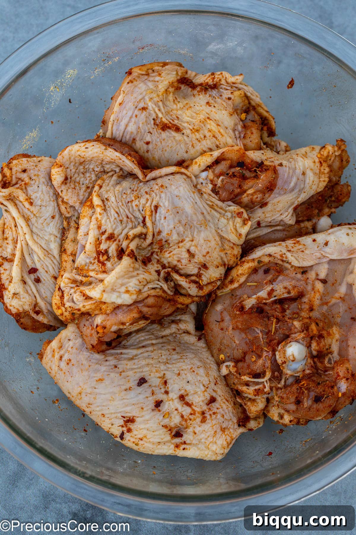 Chicken thighs generously coated in a mix of fragrant spices, ready for searing.
