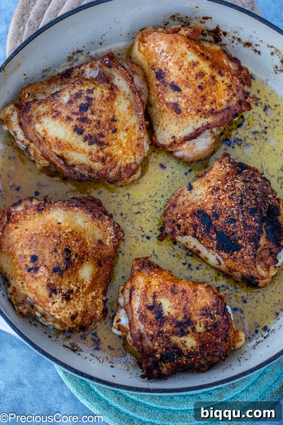 Marinated chicken thighs being seared to a golden crisp in a hot pan.