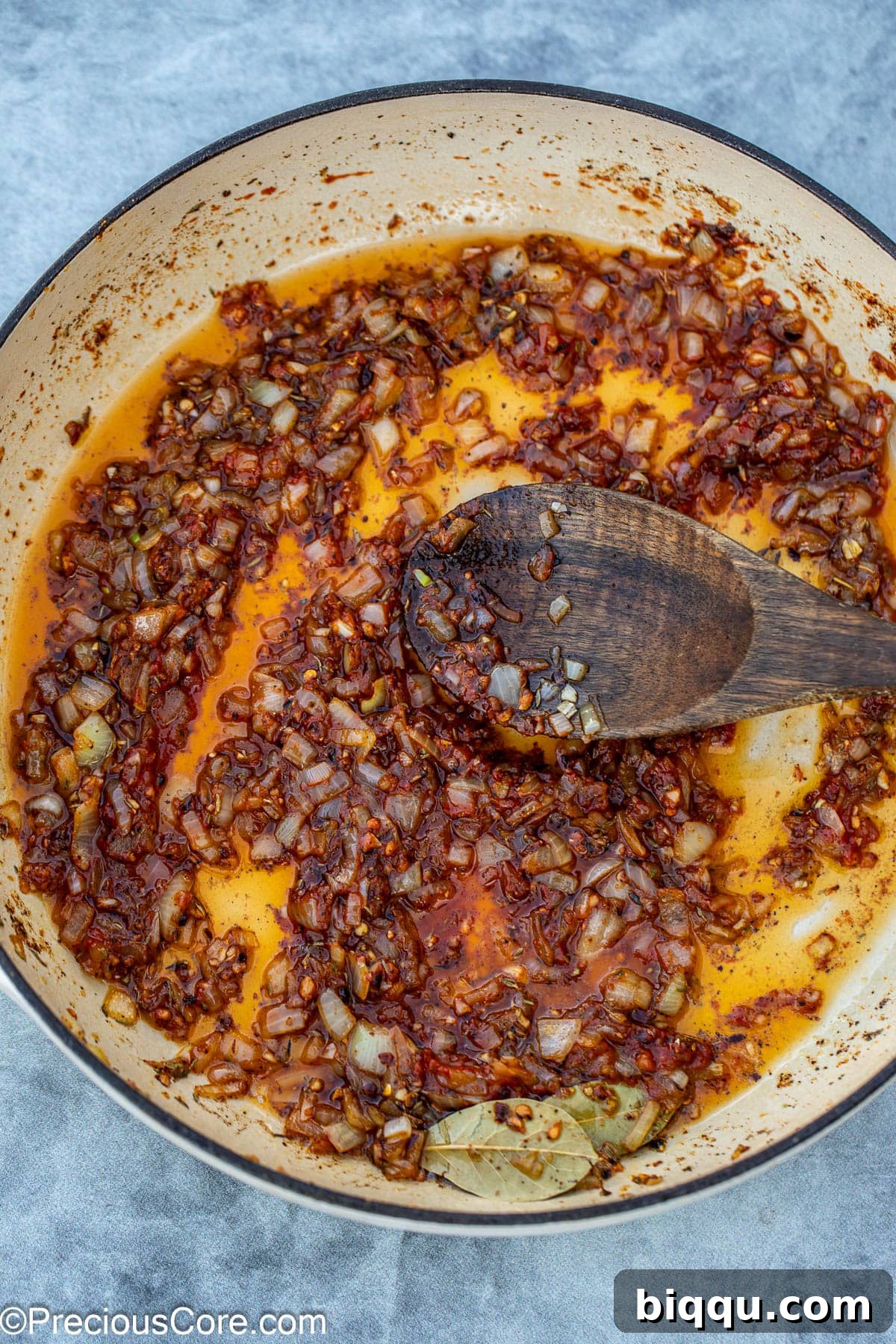 Adding rich tomato paste to the sautéed aromatics in the pan, enhancing the depth of flavor.
