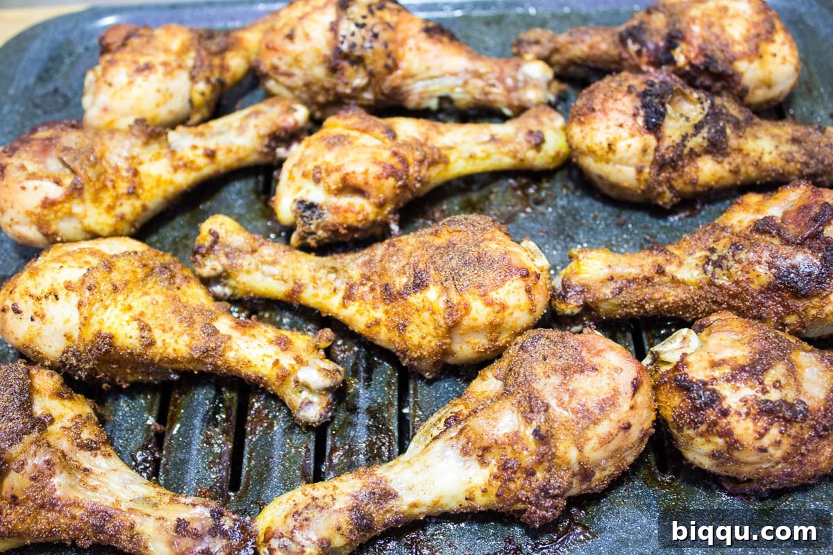 Perfectly grilled chicken drumsticks on a broiling pan, ready to eat.
