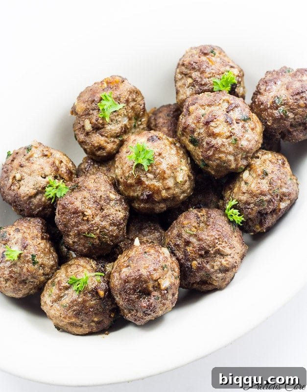 A white dish filled with beautifully cooked and browned meatballs.