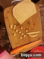 Dough being cut into rectangular Chin Chin strips with a pastry wheel