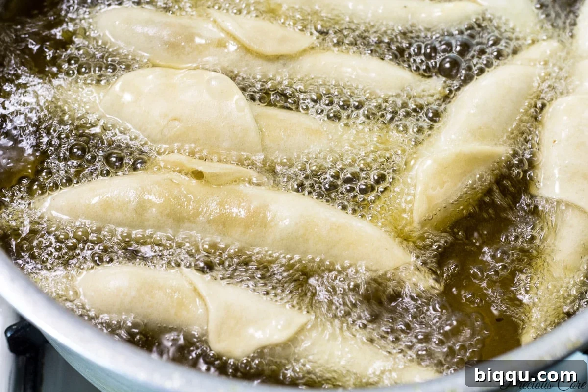 Cameroonian fish rolls being carefully fried in hot oil until they turn golden brown