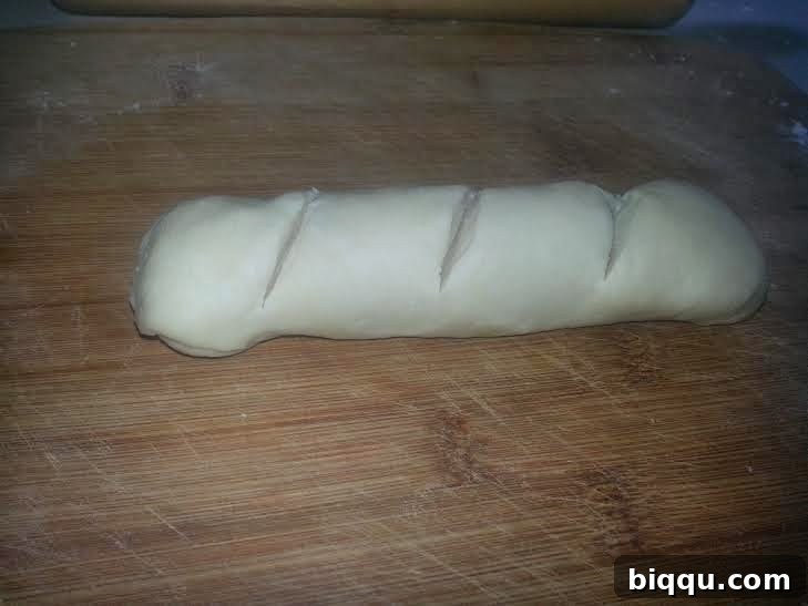 Dough log with three parallel cuts on top.