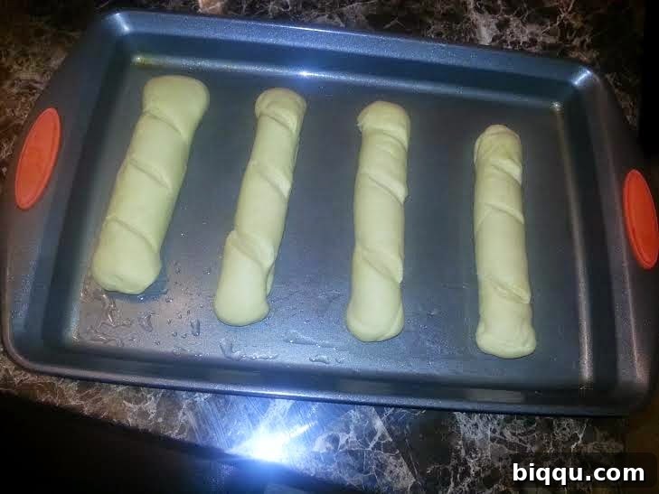 Four shaped dough pieces arranged on a greased baking tray.