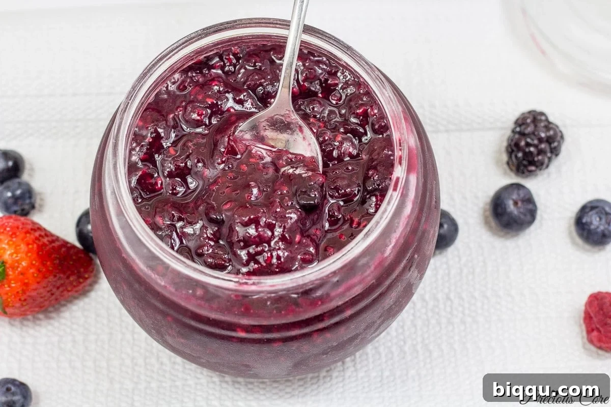 A glistening jar of homemade mixed berry jam, showcasing its rich color and inviting texture.