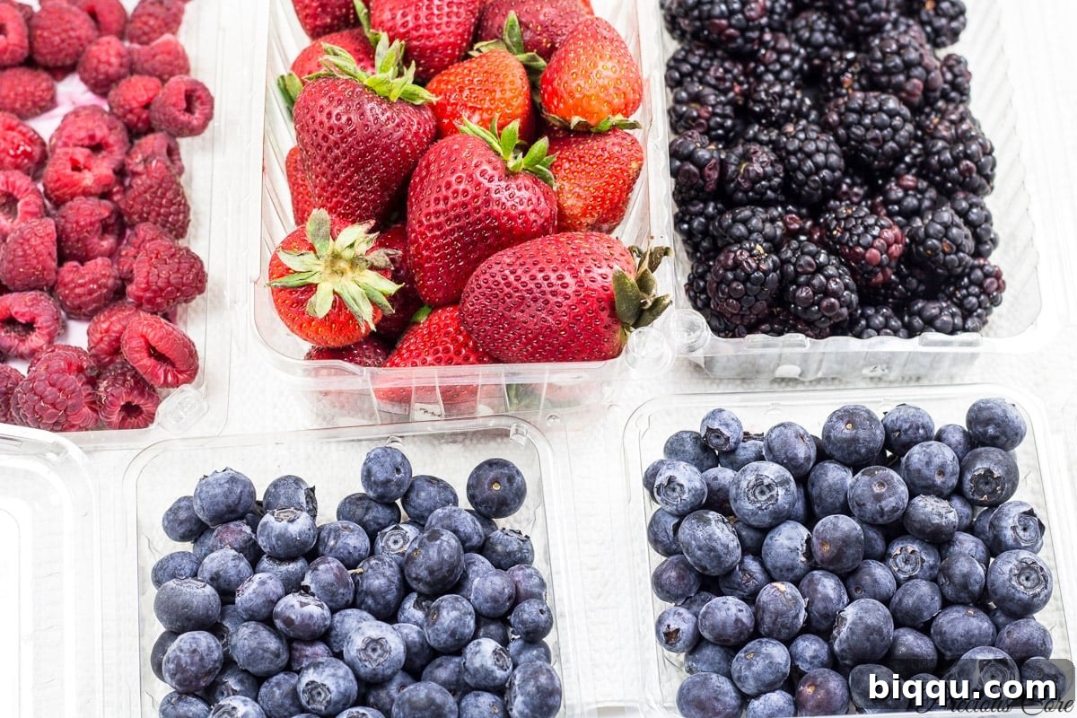 A vibrant selection of fresh strawberries, blueberries, raspberries, and blackberries laid out.