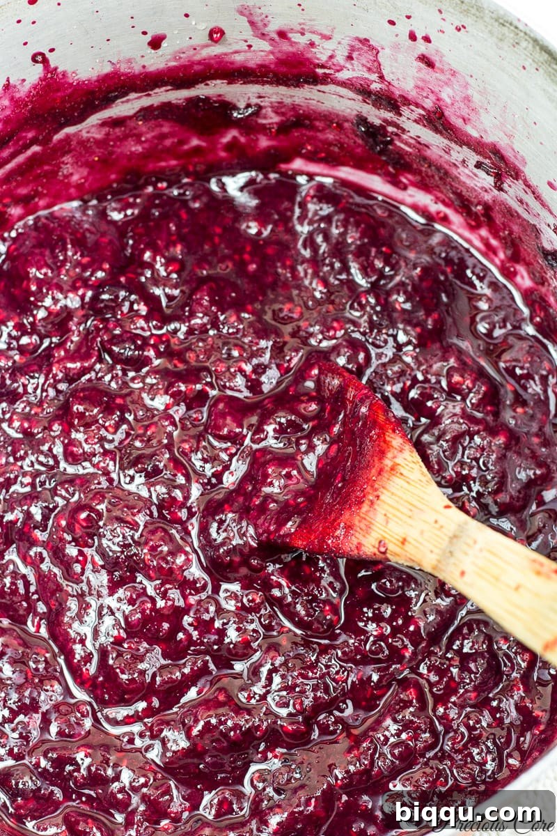 Homemade mixed berry jam bubbling gently in a pot, almost reaching its perfect gel-like consistency.