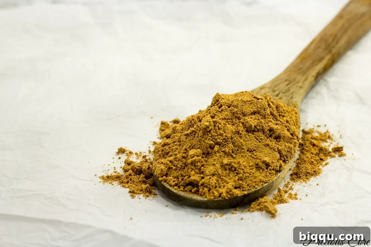 A wooden spoon generously piled high with freshly made West African Suya spice, showcasing its rich texture and color.