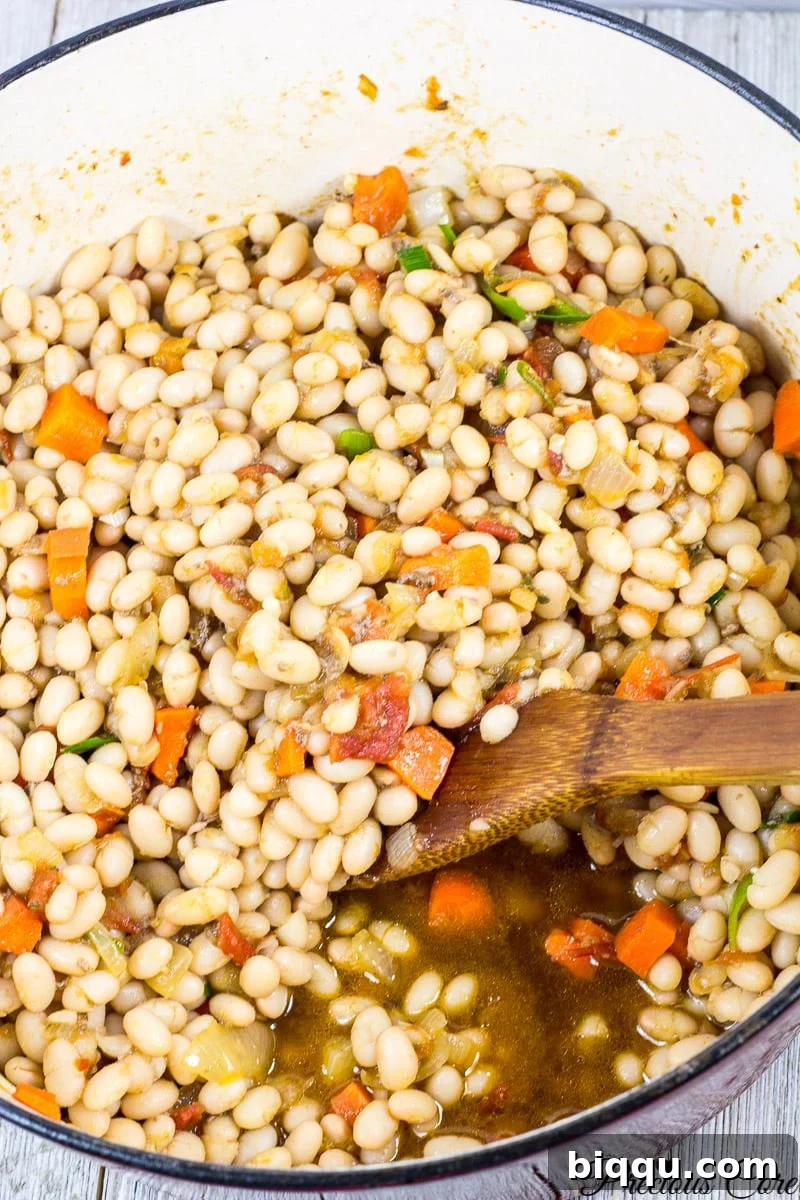 Delicious white bean stew with tomatoes and vegetables simmering in a pot