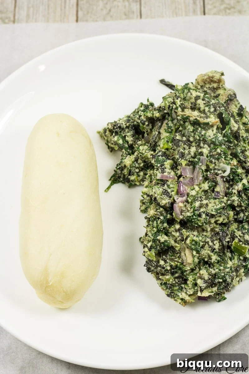 A plate of water fufu served with Ndole, a Cameroonian bitterleaf stew.