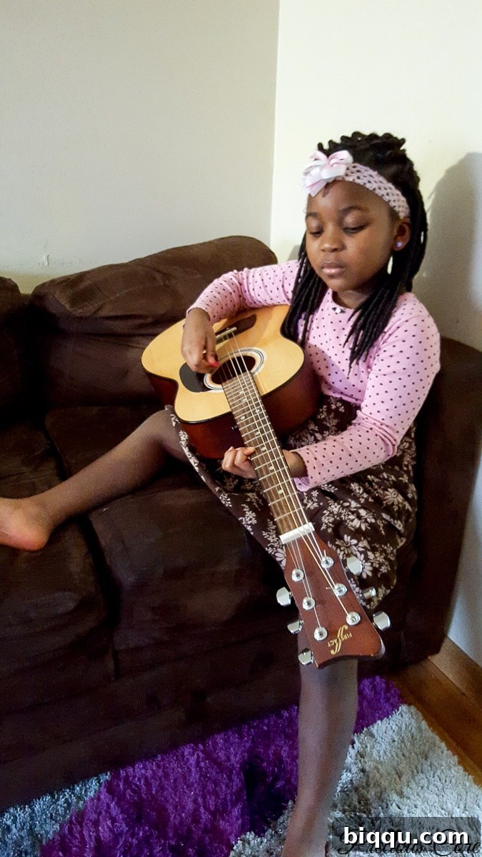 Our Inaugural Homeschool Adventure 7 A young girl joyfully learning to play the guitar, fostering her musical talent and passion.
