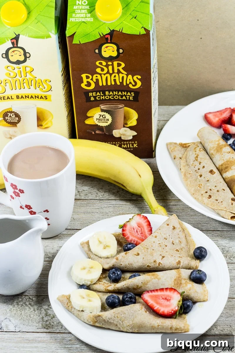 Plates of banana crepes with containers of Sir Bananas milk, garnished with fresh fruit.