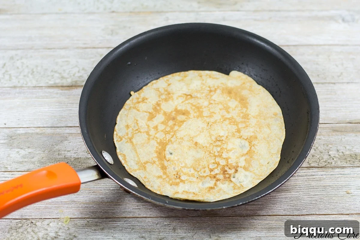 Cooking banana crepes on a hot skillet, showing the golden brown underside.